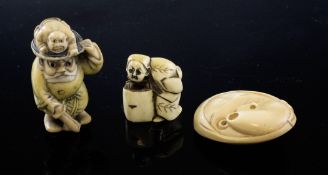 Three Japanese ivory netsuke, c.1940, the first modelled as a man with a crouching wrestler upon his