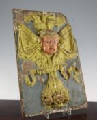 A 17th century continental carved and painted rectangular panel, decorated with a cherub mask with