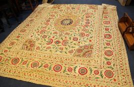 A Persian Suzani embroidered bedspread, with coloured allover floral motifs and central oval