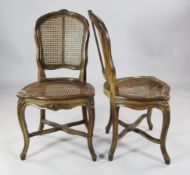 A pair of Louis XV floral carved beech occasional chairs, with caned backs and seats, on cabriole