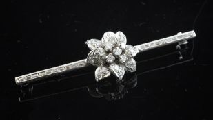 A white gold and diamond set bar brooch, with foliate central motif and bar inset with baguette