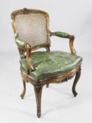 A Louis XV style beech fauteuil, with flower carved frame, caned back and green leather