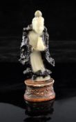 A Chinese white and black soapstone standing figure of Guanyin, Qing dynasty, holding a vase in both