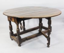 An elm and oak oval gateleg table, c.1740, the oval top above lateral drawers, on bold baluster