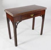 A George III mahogany games table, with folding top enclosing red leather skiver with counter wells,