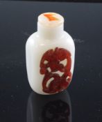 A Chinese three colour glass snuff bottle, the white body decorated with a blue and red chi-dragon