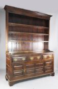 A mid 18th century oak dresser, with later three shelf rack, three long drawers and two fielded