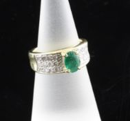 A modern 14ct gold, emerald and diamond set dress ring, with oval cut emerald weighing approximately