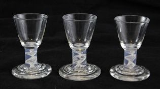 A set of three George III firing glasses, c.1765, each with a rounded funnel bowl set on an opaque