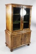 A mid 18th century crossbanded walnut bookcase, with two bevelled glazed doors and cupboard base, on