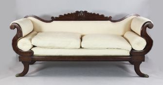 A Regency mahogany settee, with carved cresting rail, cream foliate scroll upholstery and sabre