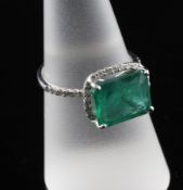 An 18ct white gold, emerald and diamond dress ring, the emerald cut stone weighing approximately
