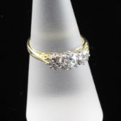 An 18ct gold and graduated three stone diamond ring, with carved shoulders and an estimated total