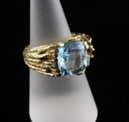 An 18ct gold and blue topaz set dress ring, with textured shank, size M.