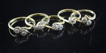 Five 18ct gold and two stone diamond cross-over rings, one with diamond set shoulders.