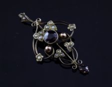 An Edwardian 9ct gold, garnet and seed pearl set pendant, of openwork scrolling design, 1.5in.