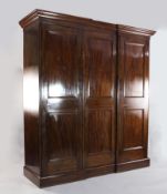 A late Victorian mahogany inverse breakfront wardrobe, fitted three panelled doors, on plinth