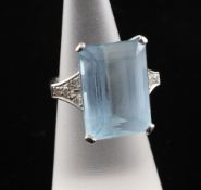 An 18ct white gold, aquamarine and diamond set dress ring, the central emerald cut aquamarine