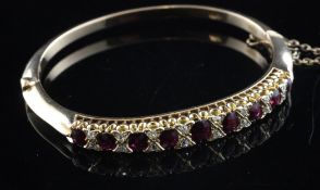 A gold, ruby and diamond set stiff bracelet, set with oval cut rubies.