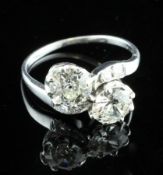 An Art Deco platinum and two stone diamond crossover ring, the total diamond weight approximately