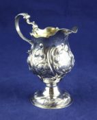 A George III silver silver pear shaped pedestal cream jug, with later embossed decoration and