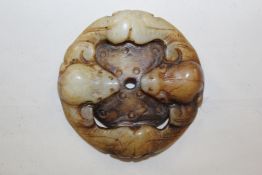 A Chinese bowenite disc, carved as two opposing bats around a central wheel, 2.1in. (5.3cm)