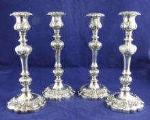 A set of four 20th century silver plated candlesticks, with turned baluster stems and embossed