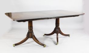 A Regency style extending mahogany dining table, with three extra leaves, with twin pillars and