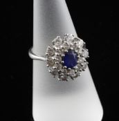 An 18ct white gold, sapphire and diamond cluster ring, of oval form, with oval cut sapphire bordered