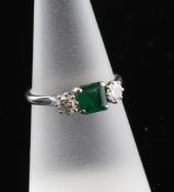 An 18ct white gold, emerald and diamond three stone ring, the central emerald flanked by round cut