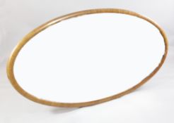 A large mid 20th century oval walnut framed wall mirror, with bevelled plate glass, the back