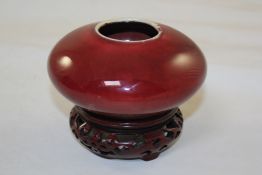 A Chinese sang de boeuf glazed censer, of compressed globular form, 4.8in. (12.2c,), wood stand