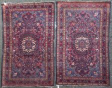 A pair of Kashan rugs, with central foliate medallion, within a field of scrolling foliage, on a red