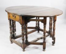 A 17th century walnut oval gateleg table, with two end drawers, on turned supports united by
