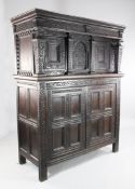 A 17th century carved oak court cupboard, with central arched panel and two cupboard doors between