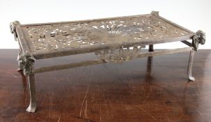 A George III rectangular pierced steel trivet, decorated with flowers, leaves and scrolls with ram`s