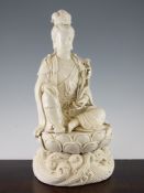 A Chinese blanc de chine seated figure of Guanyin, wearing elaborate jewellery and holding lotus