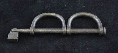 A pair of wrought iron hand manacles, with end padlock inscribed `Belmont Parish 1759`, 9in.