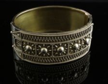 A late Victorian gold Etruscan style stiff bracelet, with cannetile work decoration,