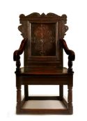 A CHARLES II OAK PANEL BACK ARMCHAIR, CIRCA 1680, Yorkshire, the shaped eared cresting above a