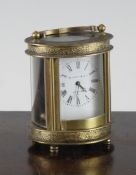 An early 20th century French brass miniature carriage timepiece, with oval case and enamelled dial