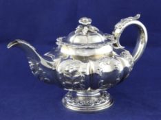 An early Victorian silver melon shaped pedestal teapot, with embossed foliate scroll decoration,