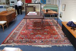 A Persian carpet, with field of scrolling foliage on a brick red ground, with three row foliate