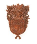 A CONTINENTAL CARVED LIMEWOOD SHIELD, EARLY 18TH CENTURY, the sunburst upper section flanked by
