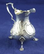 A Victorian repousse silver cream jug, of pear form, with vacant cartouche and floral decoration, on