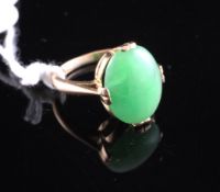 A gold and oval cabochon jadeite ring, size F.