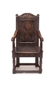 A CHARLES I CARVED OAK PANEL BACK ARMCHAIR, MID 17TH CENTURY, the arched cresting with a central