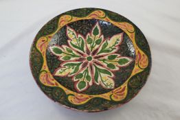 A Della Robbia pottery dish, painted in green, red, brown and yellow with an Islamic inspired flower