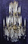 A large decorative gilt brass and lustre drop chandelier, with eighteen scroll sconces, 52in.