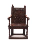 A CHARLES I OAK PANEL BACK ARMCHAIR, CIRCA 1640 the later finials above a foliate scroll and